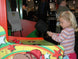 Child playing an arcade game with colorful machine and people in the background