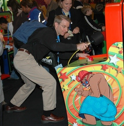 Man playing an arcade game with a cartoon character on the machine