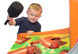 Child playing with a colorful game machine, holding a paddle.