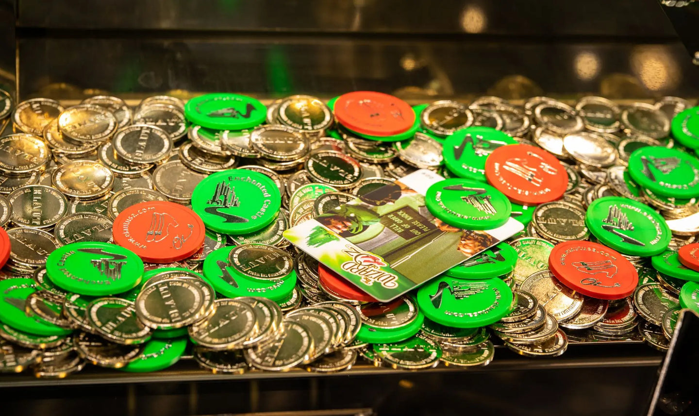 Collection of coins and tokens with green and red labels on a reflective surface