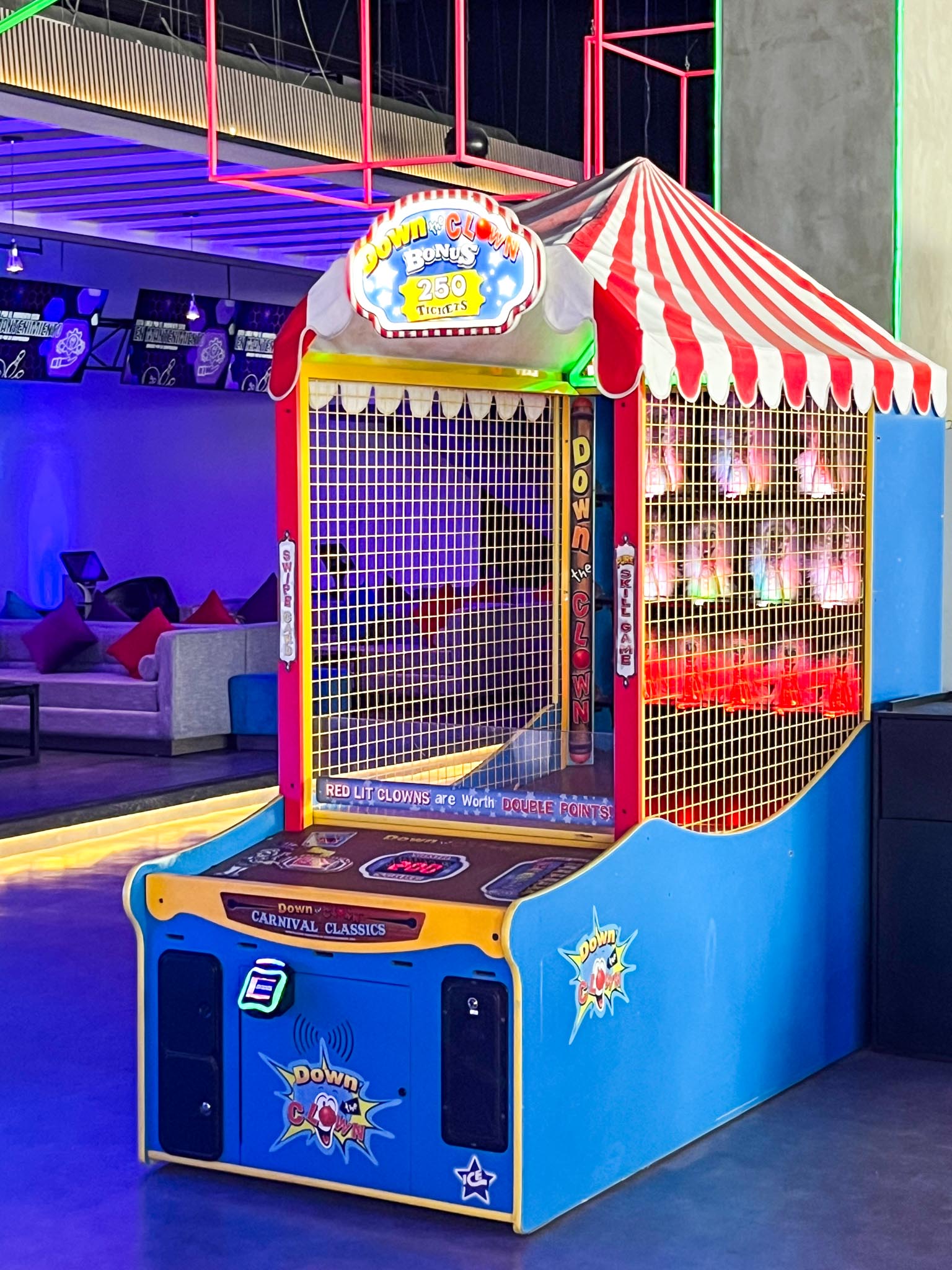 An arcade game titled 'ICE Down The Clown' featuring a colorful cabinet with a carnival-style canopy, LED lighting, and a digital score display.