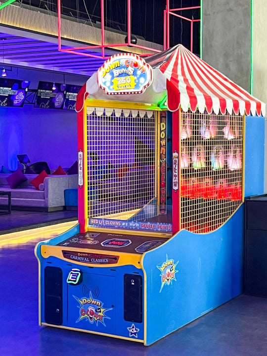 An arcade game titled 'ICE Down The Clown' featuring a colorful cabinet with a carnival-style canopy, LED lighting, and a digital score display.