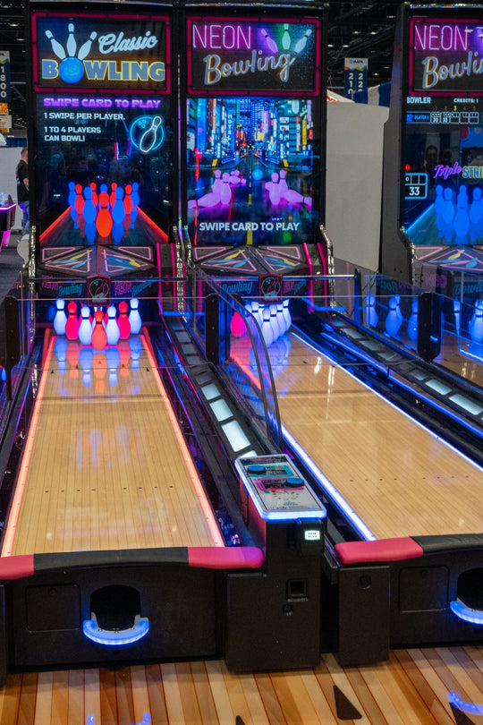 An arcade version of bowling game with neon lights and a large screen monitor.