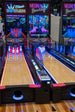 An arcade version of bowling game with neon lights and a large screen monitor.