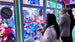 People playing claw machine games in an arcade setting