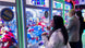 People playing claw machine games in an arcade setting