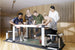 Group of people playing a game on a small sports court with a wooden wall background