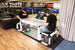 Two people playing air hockey in an indoor setting with various advertisements on the walls.